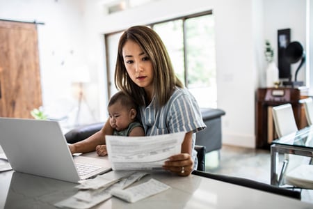 Working parent holds a child and looks at a piece of paper comparing Netlify vs WordPress